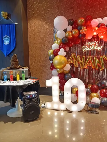 The full party setup, complete with a balloon arch, neon birthday sign, and light-up marquee numbers, all complementing the magical wizard theme for an unforgettable celebration.