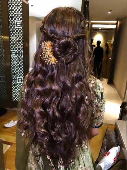 A back view of the reception guest's hairstyle, showing a braided half-updo with a gold accessory.
