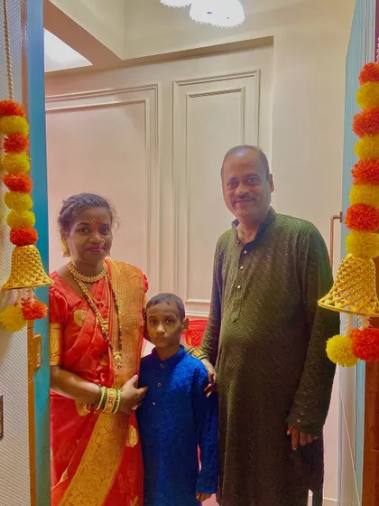 The Chalke family at the entrance of their new home, decorated with traditional marigold garlands for the Griha Pravesh ceremony.