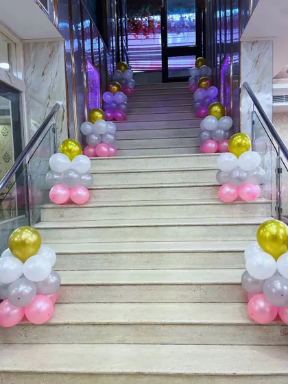 Staircase decoration with pink, white, and gold balloon clusters for a party entrance.
