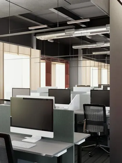 The open-plan workstation area in a modern office, designed for collaboration and focus. The layout maximizes natural light from the large windows, with exposed ceiling ducts adding an industrial touch.