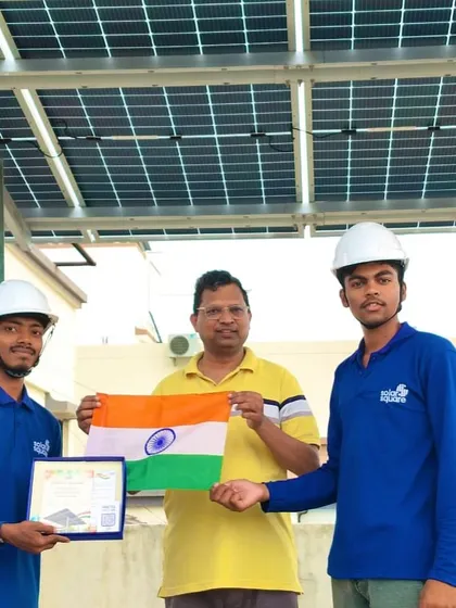 Our crew in hard hats with a satisfied customer, holding the Indian flag to celebrate his new solar investment.