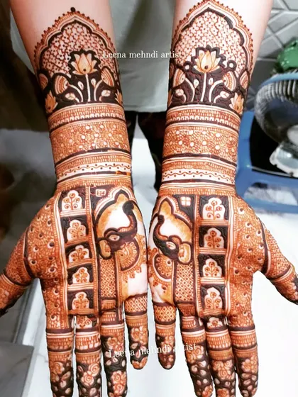 A beautiful bridal design featuring elephants within a jharokha grid. The upper arms are adorned with lotus motifs, creating a cohesive and traditional piece of art.