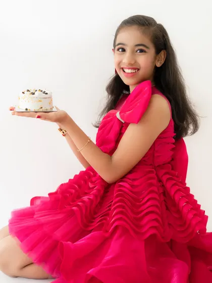 A bright and happy portrait of the birthday girl in her vibrant pink dress. Her beautiful smile lights up the photo.