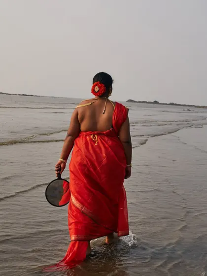 A narrative shot of the subject walking into the water, holding a mirror. This conceptual image is about reflection, identity, and embracing one's own story.