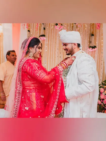 The bride's turn to place the garland on the groom during the Varmala, a moment of mutual respect and acceptance.