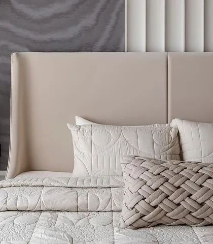 A close-up of the bedroom, showing the interplay between the dark, wavy wallpaper, the vertically fluted wall panel, and the woven texture of the cushion. This highlights the importance of layering textures for a rich, sensory experience.