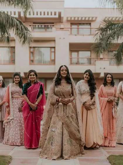 A lovely group portrait of the bride with her bridesmaids and family, all dressed in beautiful coordinated outfits.
