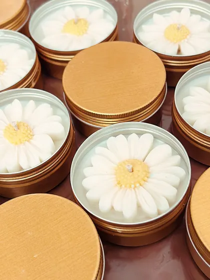 My daisy candles in travel-friendly tin containers. These are perfect for bulk orders as they are durable and easy to customize.