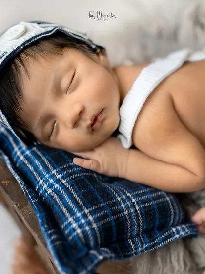 A close-up of this tiny dreamer, fast asleep on a plaid pillow. The details, from his striped hat to his tiny toes, are just precious.