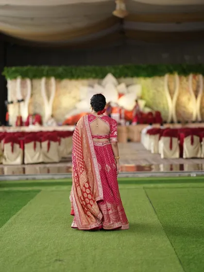 A back view of a client wearing a stunning pink bandhani lehenga for a wedding.