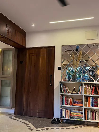 The entryway of this home features a solid wood door, a custom bookshelf, and a decorative beveled mirror wall that adds depth and elegance to the space.