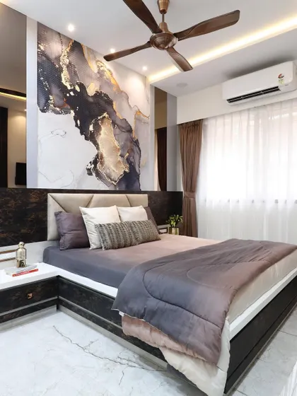 A master bedroom featuring a dramatic, custom wallpaper with black and gold abstract art behind the bed. The design is balanced with dark wood furniture and mirrored panels for a touch of glamour.