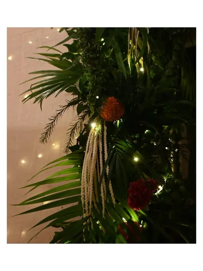 This close-up shows the rich textures of our Ganpati floral decor. We layered different types of palm leaves, ferns, and marigolds, intertwining them with delicate white tuberoses and warm fairy lights to create a lush and natural-looking festive arrangement.