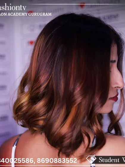 A student's work showcasing a professional balayage technique. The image displays a beautiful blend of brown and caramel tones with soft, face-framing curls.