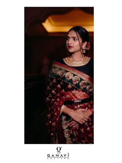 Bindu redefining elegance and grace in a deep red embroidered saree. The ensemble is paired with a simple black blouse and a belt, creating a chic and uber-stylish look.