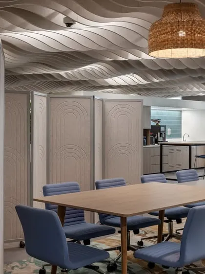 A meeting area with a wavy, sculptural ceiling and woven pendant lights. The space can be enclosed with movable acoustic partitions, allowing for both open collaboration and private discussions.