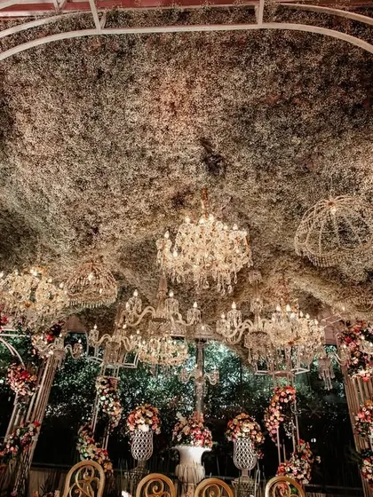 Looking up into the canopy of the mandap, this shot reveals the intricate web of foliage and the dozens of crystal chandeliers that create a magical, starlit effect.