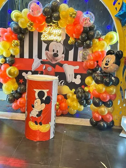 A classic Mickey Mouse theme birthday party for a 3-year-old. This setup includes character cutouts, themed balloon pillars, a marquee number '3', and a full backdrop for the cake table.