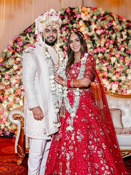 The first official portrait as husband and wife. Akanksha and Dishant stand together after their Jaimala ceremony, framed by a stunning floral arch, a timeless photo for their family album.