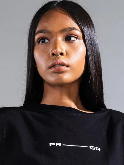 A direct, powerful headshot where the makeup is clean and minimal, with a focus on perfected skin. The sleek hair frames the face, creating a strong look for this apparel campaign.