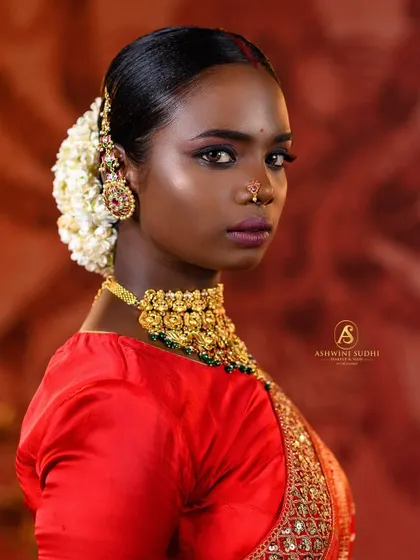 A side profile that highlights the traditional hair bun adorned with fresh flowers (gajra) and the elegant earring, key elements of a South Indian bridal look.