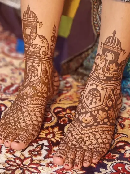 A beautiful bridal foot design with elephants and jhumkas, set against a lovely patterned rug.