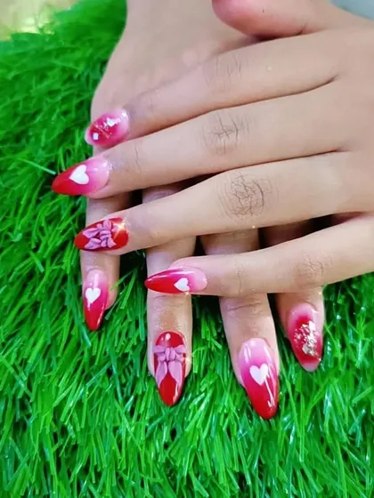 A romantic Valentine's Day design with red ombre, heart motifs, and a 3D bow design on the accent nails.