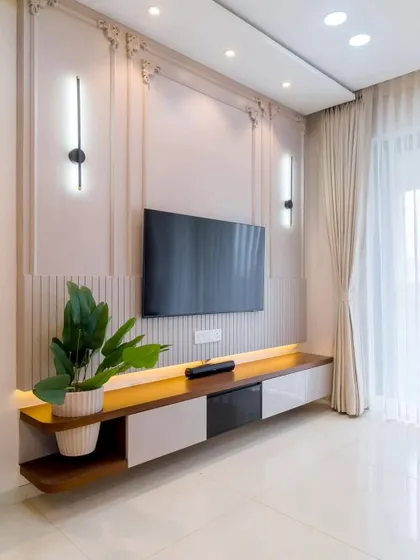 This elegant TV unit features a floating dual-tone console in wood and white, set against a wall with classic molding and fluted panel details. The vertical wall sconces add a touch of symmetrical grace to the setup.