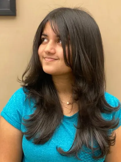A side view of a client's new haircut, showing how the layers and bangs work together to create a beautiful, flowing style.