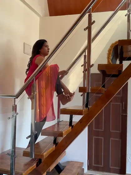 A moment of pause on the stairs, using the railing for a creative hip-opening stretch.