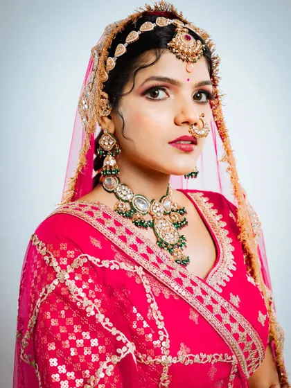 A close-up of the Marvadi bridal look, showing the intricate details of the jewellery and the vibrant pink fabric of the lehenga.