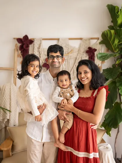 A picture-perfect family of four. The parents are holding their two children, and everyone is looking at the camera with a happy, relaxed smile.