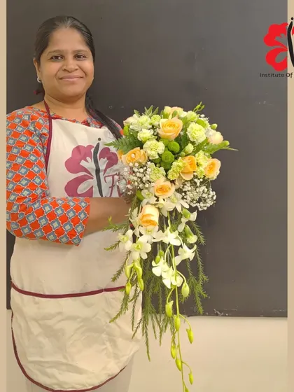 A student showcases her lovely cascading bridal bouquet. The design uses soft peach roses and white dendrobium orchids to create a classic and romantic feel, perfect for a wedding.