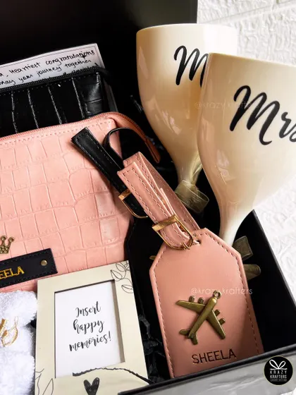 A close-up on the personalized details of the couple's travel hamper, showing the names on the luggage tag and pouch.