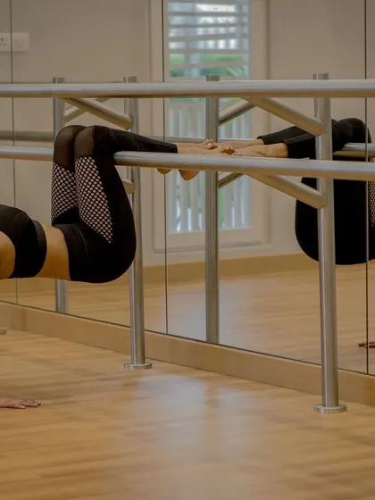Using the studio barre to explore a deep backbend. Props are not a sign of weakness; they are smart tools that allow us to safely explore the full potential of a pose.