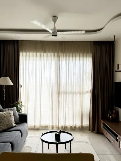 A full view of the living room, showcasing the curved ceiling, modern TV unit, and layered curtains.