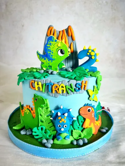 Stomp, chomp, and roar! A dinosaur cake featuring a volcano and several friendly, colorful dinos for a 2nd birthday.