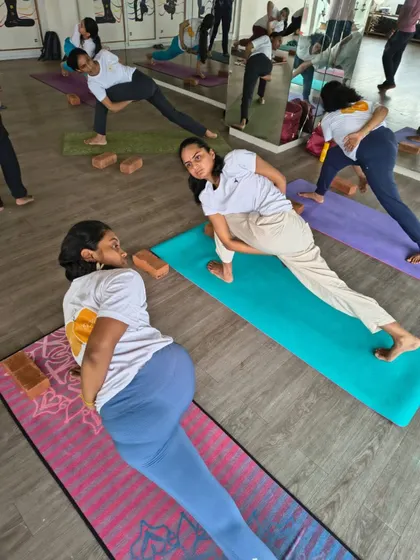 A group of TTC students practices a bound twisting lunge, building strength, balance, and flexibility. The interaction between students fosters a sense of community and shared growth.