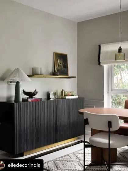 A black fluted sideboard with a brass-finished base, as seen in an Elle Decor feature. This piece adds texture and modern sophistication to the dining space.