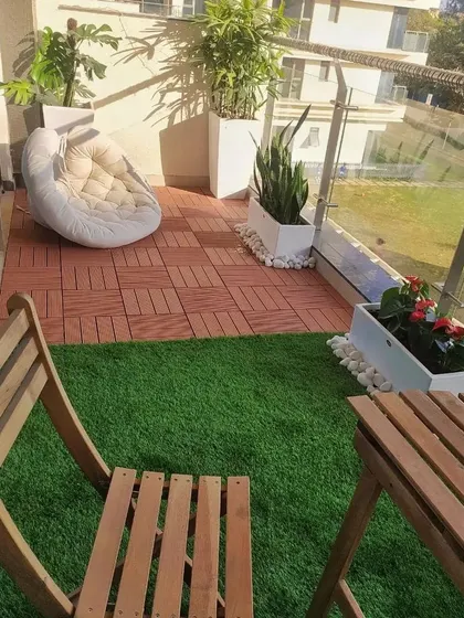 A view from the seating area of this small balcony, showing how even a compact space can accommodate a comfortable chair, a small table, and a variety of plants like snake plants and monstera.