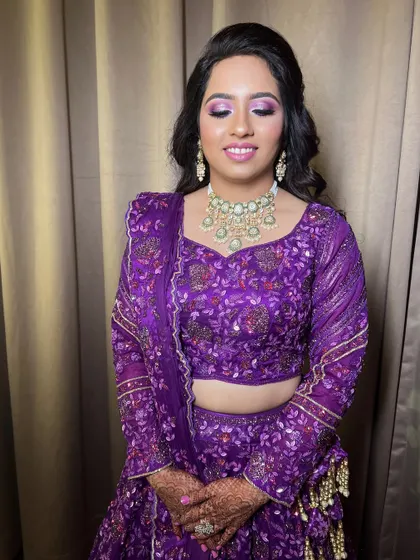 A glamorous look for a Sangeet or reception, featuring a purple lehenga and dramatic eye makeup.