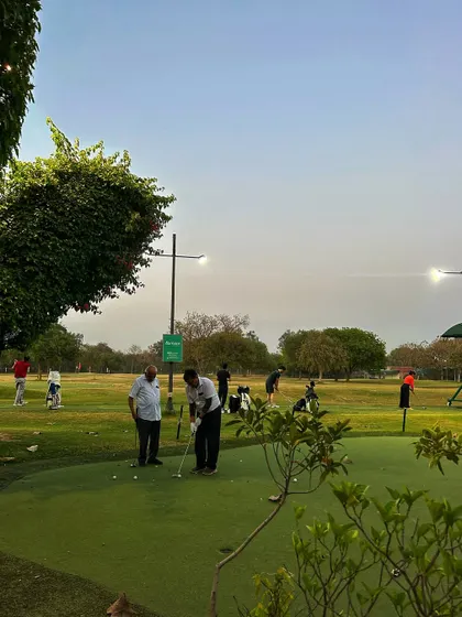 Two men practice on the putting green as evening approaches.