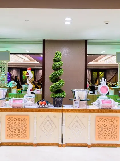 A colourful and lively 'Sweet' and 'Farsan' station. The bright decor and spiral topiary add a playful element to the traditional snack and dessert counters.