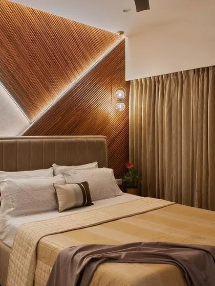 The master bedroom in this project features a striking headboard wall with geometric wood paneling and integrated accent lighting, creating a warm and inviting atmosphere.