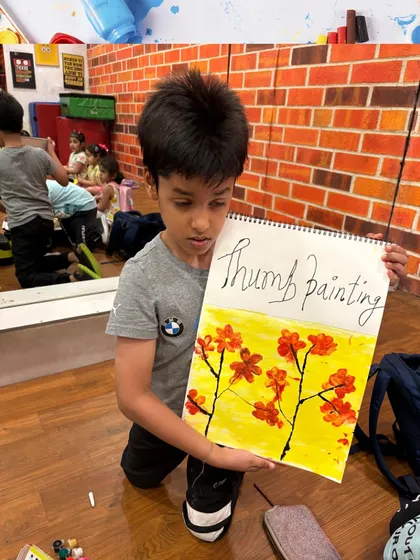 This student shows his completed thumb painting artwork. This technique is great for sensory learning and creating unique textures.