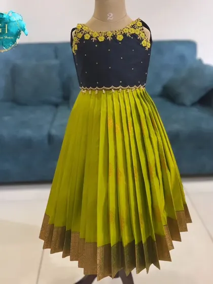 Bold and beautiful. This custom frock combines a navy blue embroidered crop top with a vibrant lime green pleated skirt, finished with a traditional gold border. It's a modern take on classic ethnic wear.