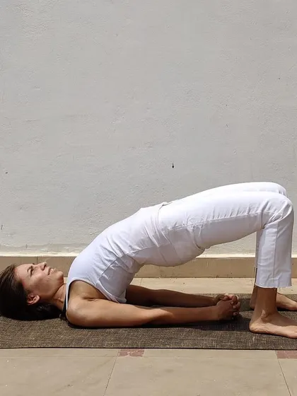 Setu Bandhasana, or Bridge Pose, is a gentle backbend that strengthens the glutes and opens the chest. A great tip for beginners is to place a block between the thighs to keep the knees from splaying out.