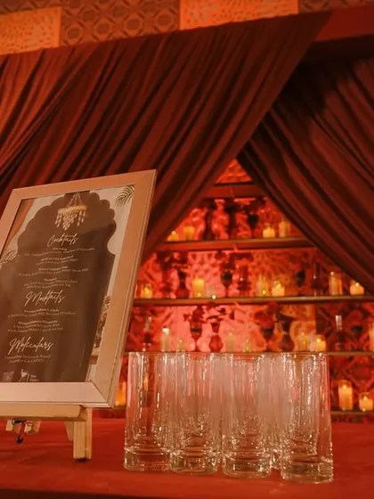 The bar area, with a framed menu and a miniature ferris wheel prop, set against the glowing, candle-lit bar back.