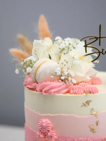 The top of the blush and gold cake, showing the beautiful arrangement of white roses, baby's breath, and dried grasses.